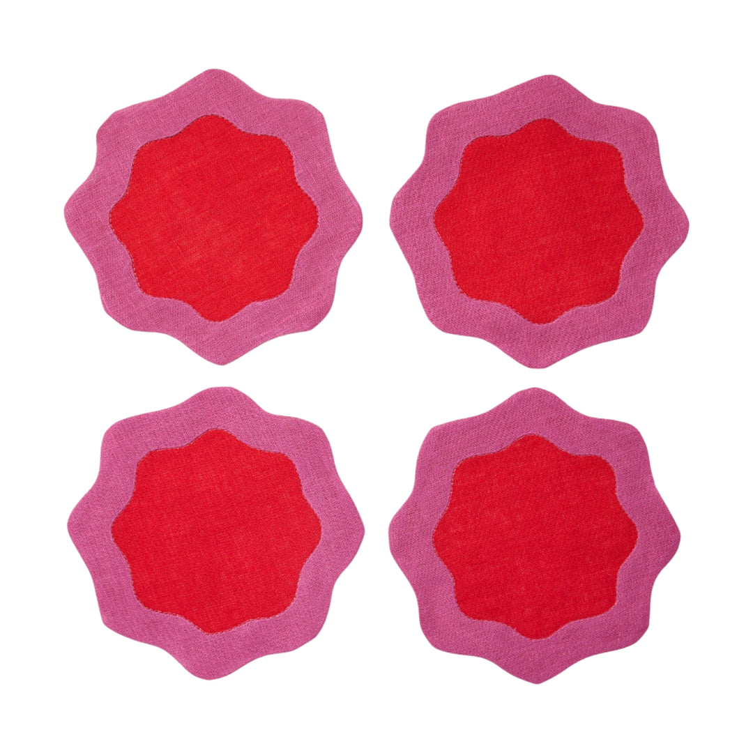 Four red coasters with pink wavy edges on a white surface