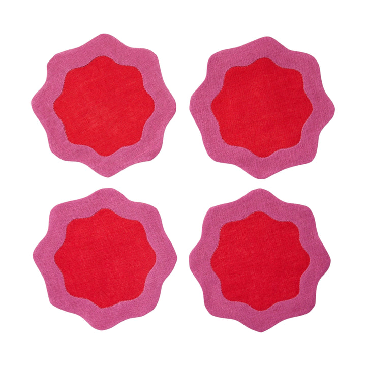 Four red coasters with pink wavy edges on a white surface