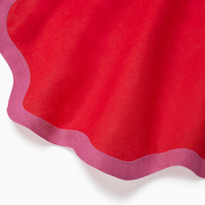 Close-up of red fabric with a scalloped pink edge on a white background