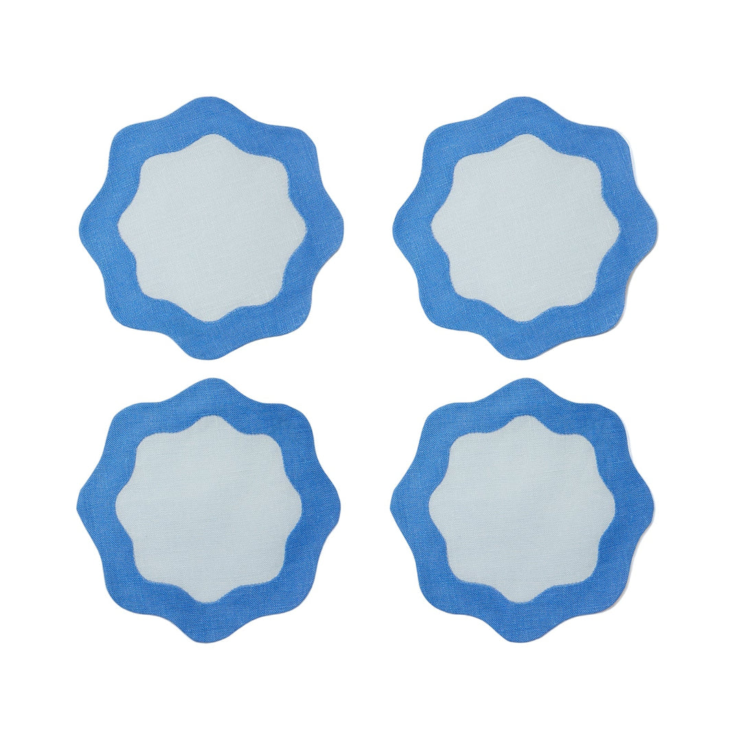Four blue coasters with light blue centers and wavy edges on a light gray surface