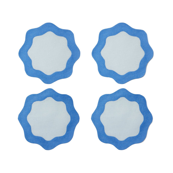 Four blue coasters with light blue centers and wavy edges on a light gray surface