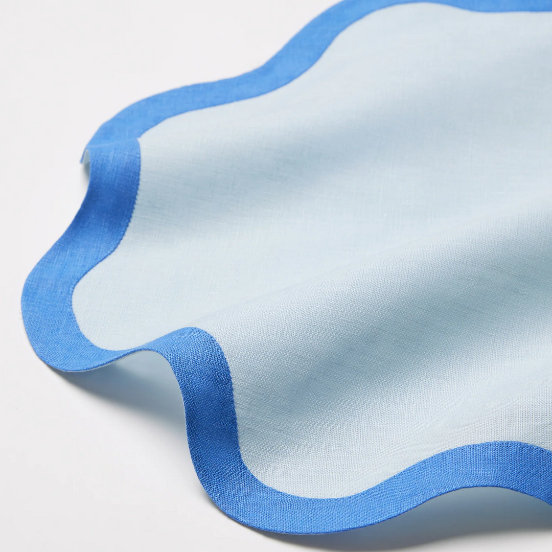 A light blue cocktail napkin with a bright blue wavy edge