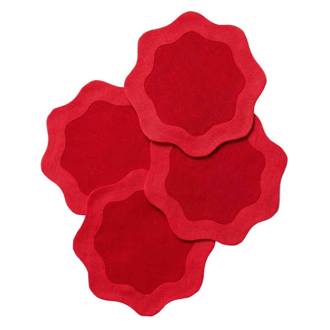 Four red coasters with deeper red centers and wavy edges on a white surface