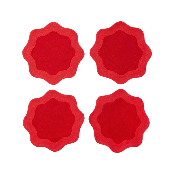 Four red coasters with deeper red centers and wavy edges on a white surface
