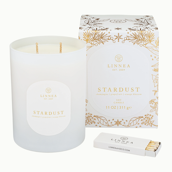 LINNEA Stardust candle with  gilded holiday packaging and matches on a white background