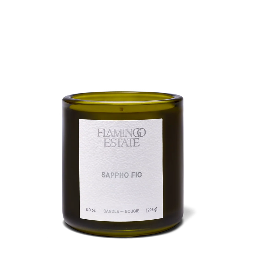 An 8.0 oz glass jar candle by Flaming Estate in the Sappho Fig scent, featuring an olive green glass container and a white paper label