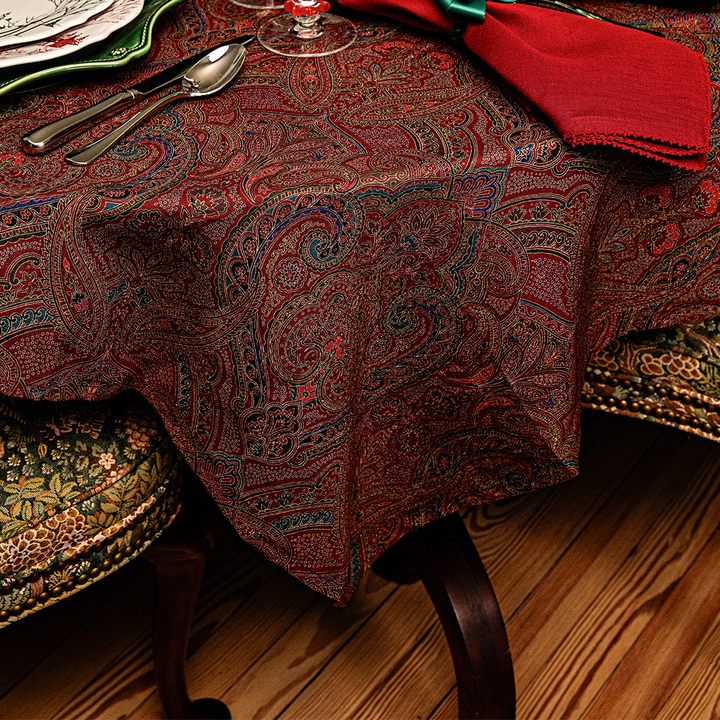 Patterned tablecloth on a wooden table with chairs.
