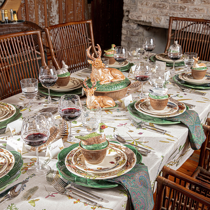 Decorative table setting with deer figurine, wine glasses, and place settings in a rustic dining room.
