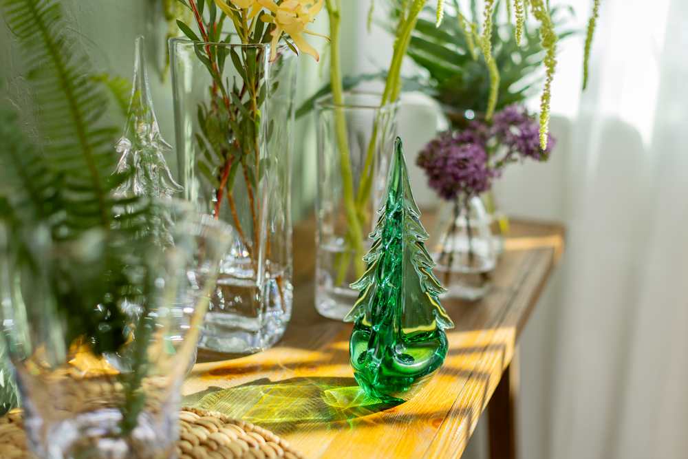 Decorative glass trees and vases on a wooden table with plants.