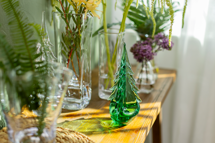 Decorative glass trees and vases on a wooden table with plants.