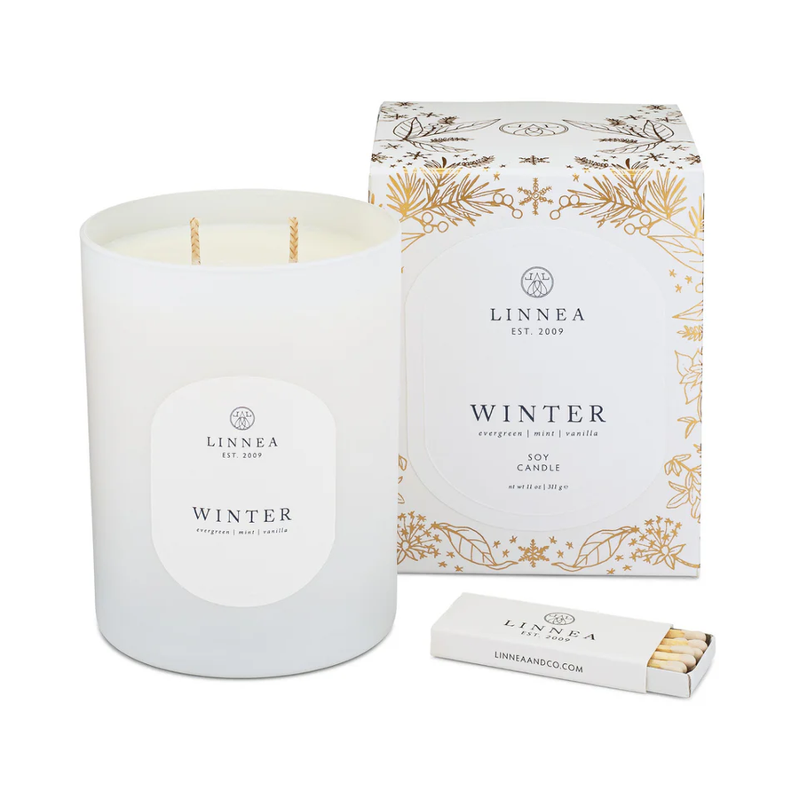 LINNEA Winter candle with gilded holiday packaging and matches on a white background