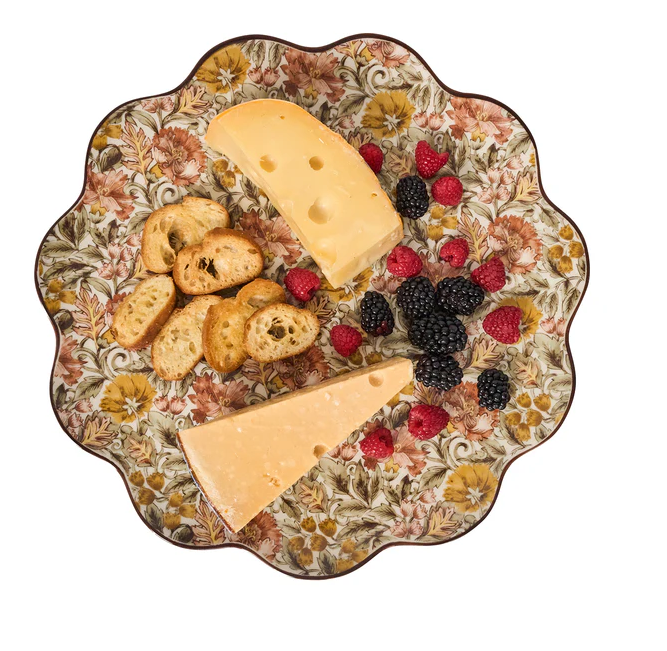 Decorative platter with cheese, crackers, and berries on an amber floral patterned background