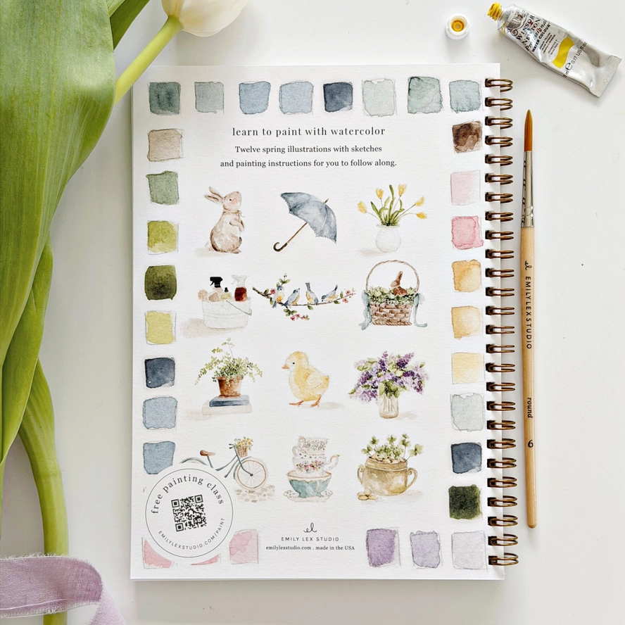 spring themed watercolor illustrations on a book with a paintbrush and watercolor bottle.