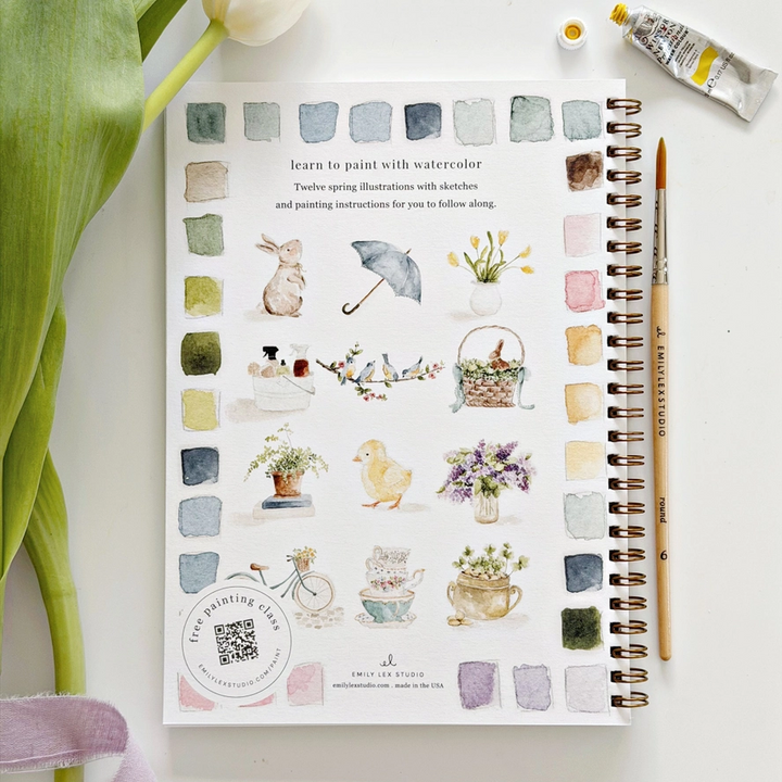 spring themed watercolor illustrations on a book with a paintbrush and watercolor bottle.