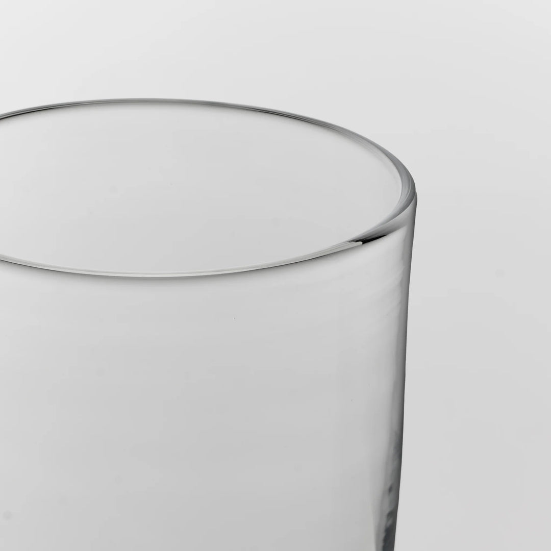 Close-up of a clear glass tumbler showing the rim and side against a light gray background.