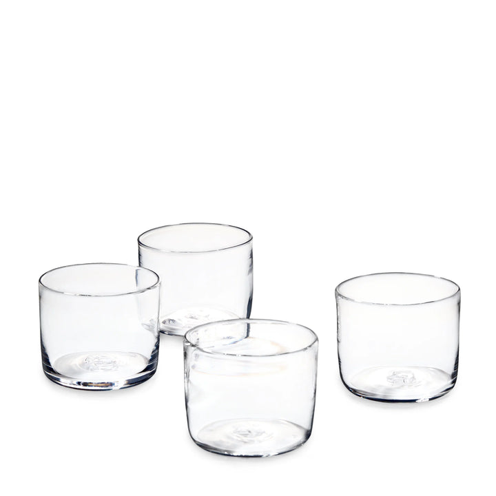 Four clear lowball glasses arranged on a plain white background.