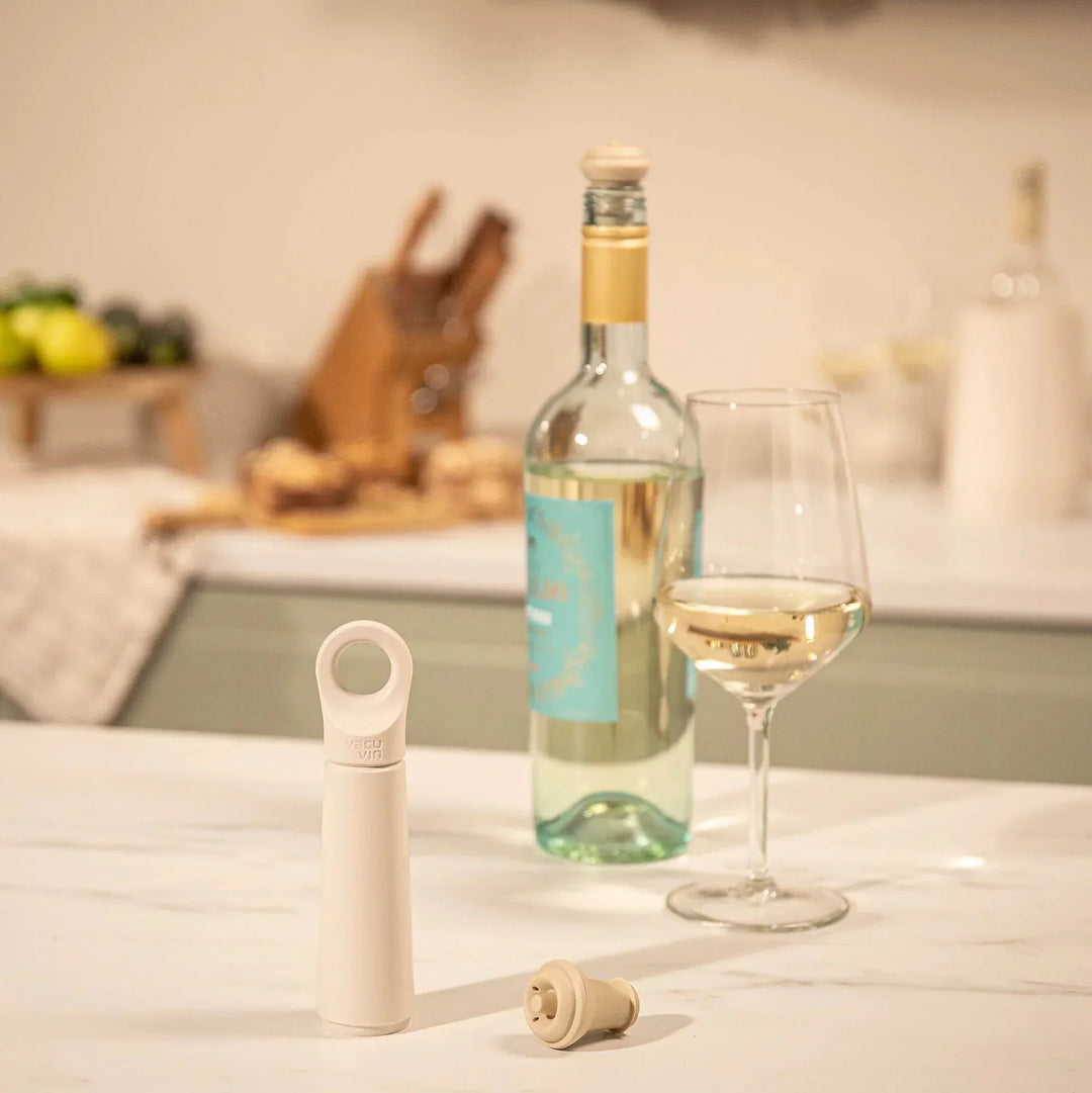 Wine bottle, glass, and vacuum stopper set on a table 