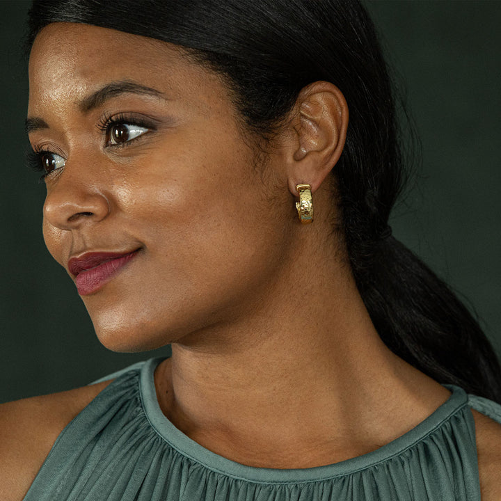 Woman wearing gold hoop earrings with a dark background
