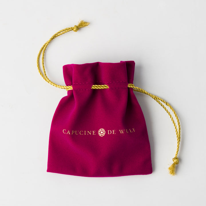 Maroon drawstring bag with gold cord and the capucine de wulf logo 