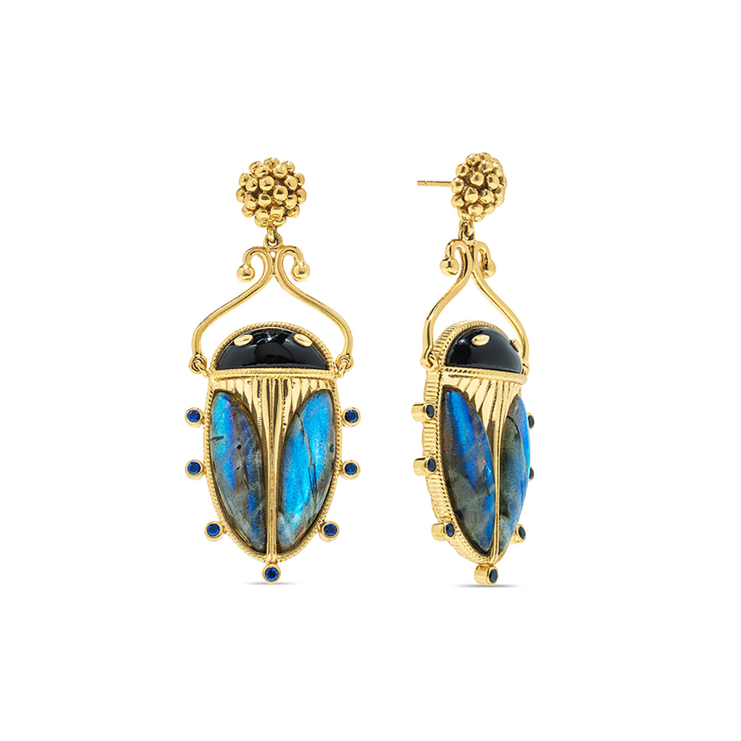 Gold scarab shaped earrings with blue gemstones on a white background