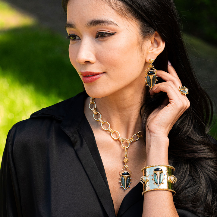 Woman wearing gold jewelry with scarab design outdoors
