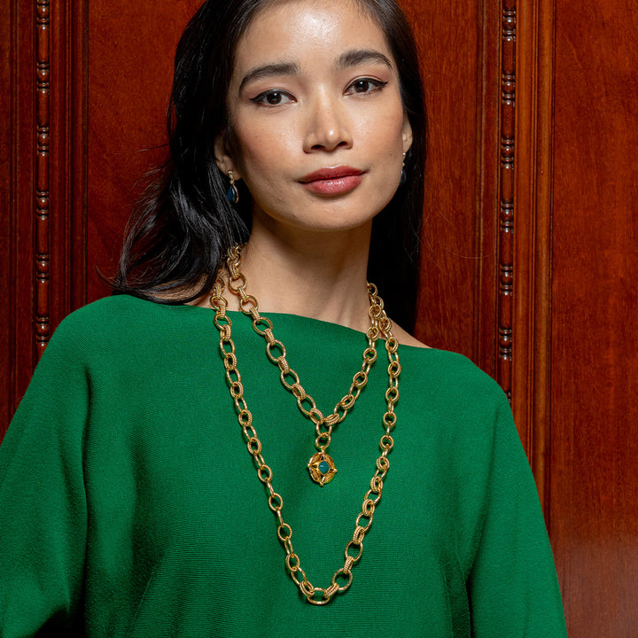 Woman wearing a gold chain necklace with a green pendant 