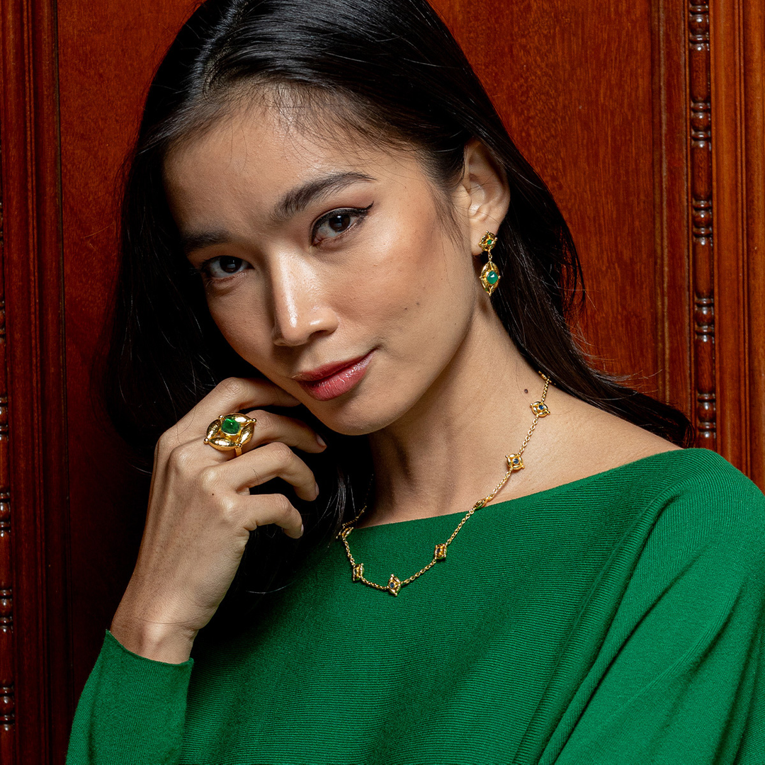 Woman wearing green jewelry against a wooden background