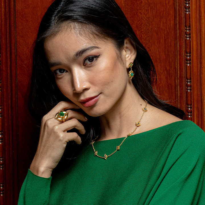 Woman wearing green jewelry against a wooden background