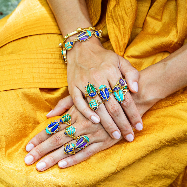 Close-up of hands wearing teal and blue gemstone rings and bracelets 