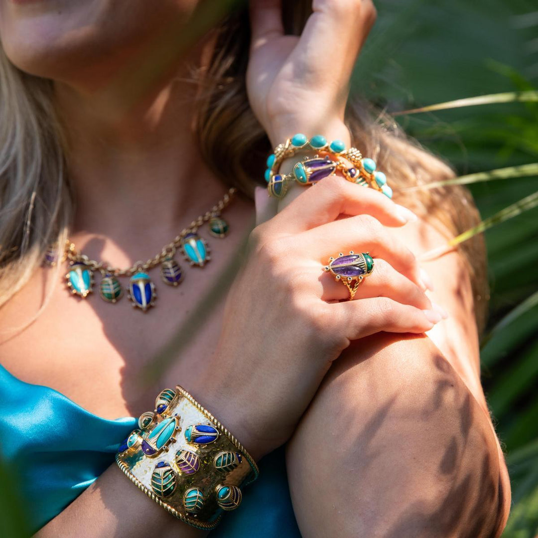 Woman wearing green and purple beetle jewelry with a natural background
