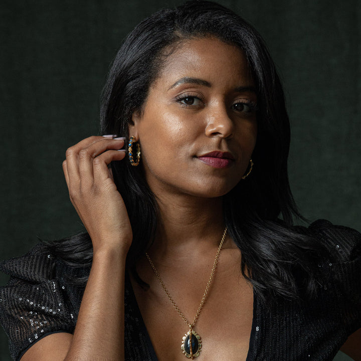 Woman wearing a blue and gold earring and a matching necklace