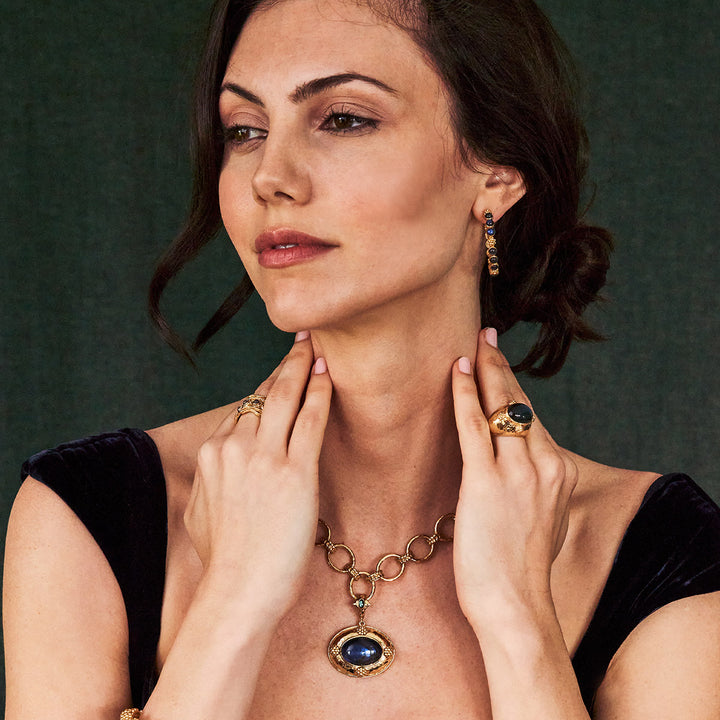 Woman wearing blue and gold jewelry with a dark background