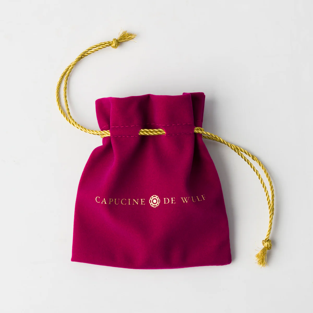 Maroon drawstring bag with gold cord and the Capucine de Wulf logo