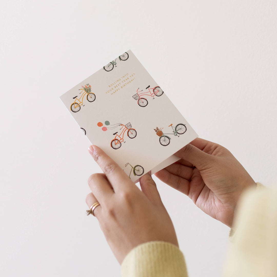 Hand holding a small notebook with bicycle illustrations on a light background