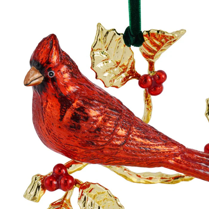 Red cardinal bird ornament with gold leaves and red berries on a white background