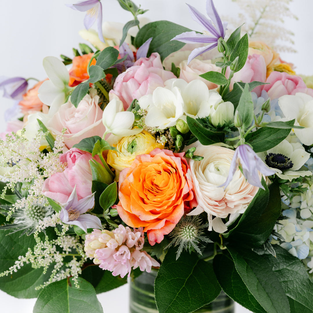 a fine flowers bouquet of roses, purple hyacinth, peonies, knotweed flower, thistle, ranunculus, and clematis.