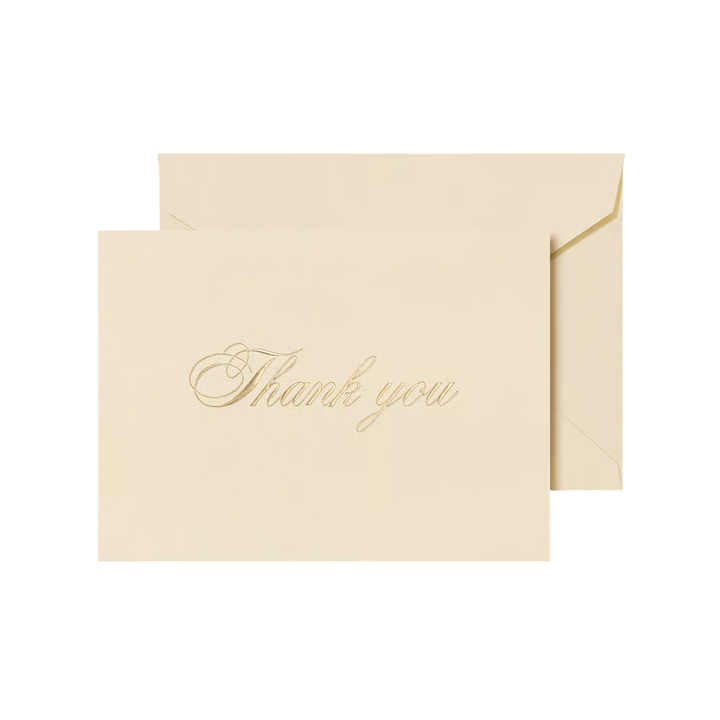 Beige card with 'Thank you' script engraved in gold ink on an envelope