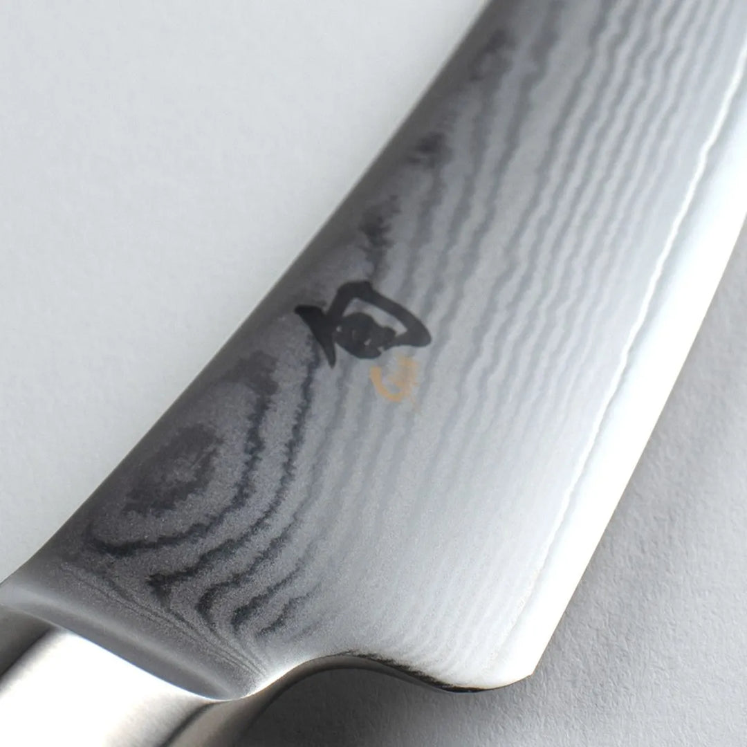 Close-up of a chef's knife with a Shun brand logo 