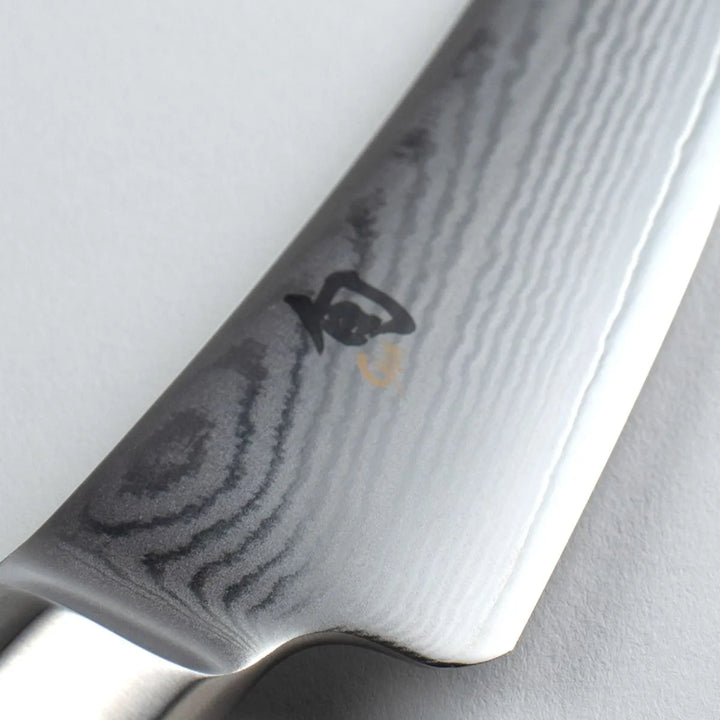 Close-up of a chef's knife with a Shun brand logo 