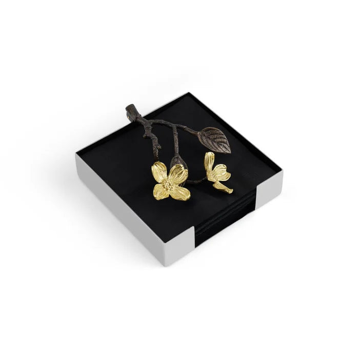 silver npakin holder with a bronze weight shaped like a twig with leaves and gold dogwood flowers