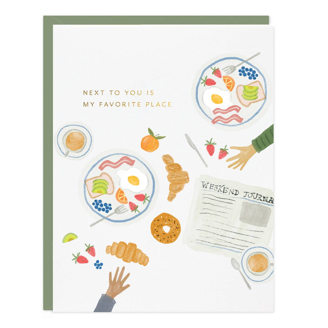 Greeting card with illustrations of food and a newspaper, featuring the text 'Next to you is my favorite place'.