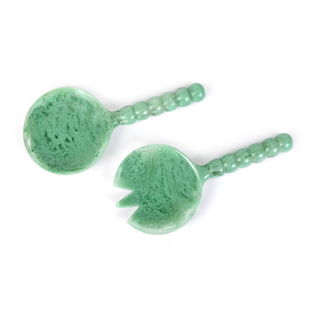 Two green stone serving utensils, one round spoon and one serving piece with a cutout, featuring textured marbled green stone and beaded handles, shown on a white background.