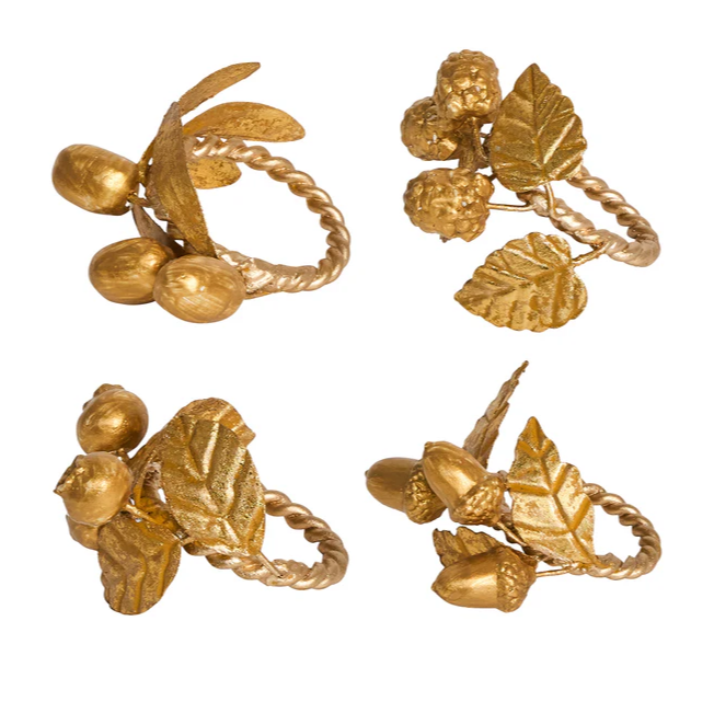 Four gold napkin rigs designed with fall leaves and each with different fruits: olives, rasperries, blueberries, and acorns.