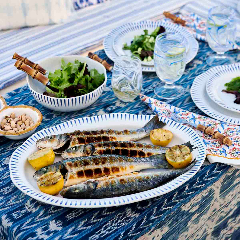 Juliska Sitio Stripe Delft Blue Platter on a table with bowls and place settings stemless marbled wine glasses