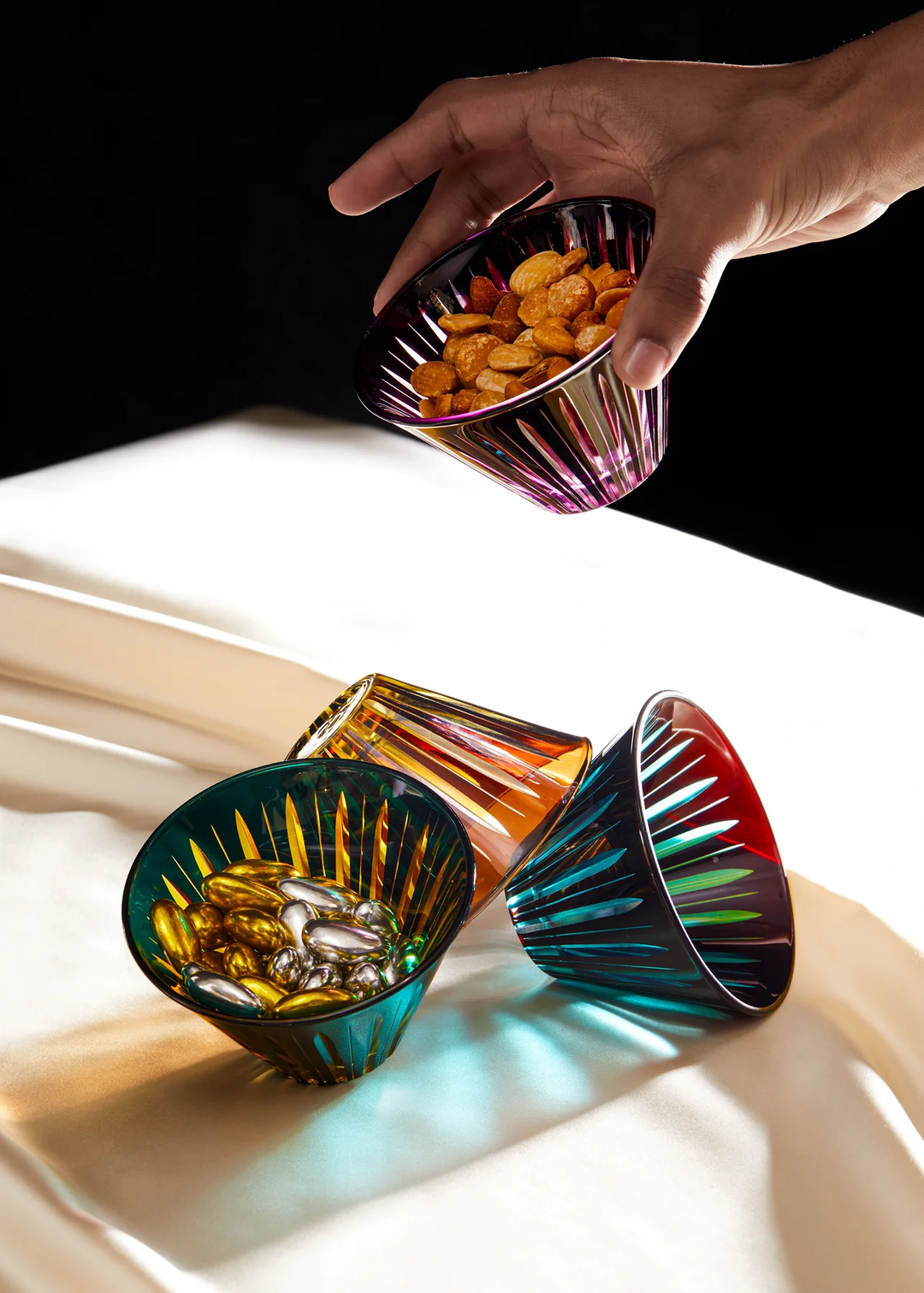 Colorful glass bowls with snacks on a white surface