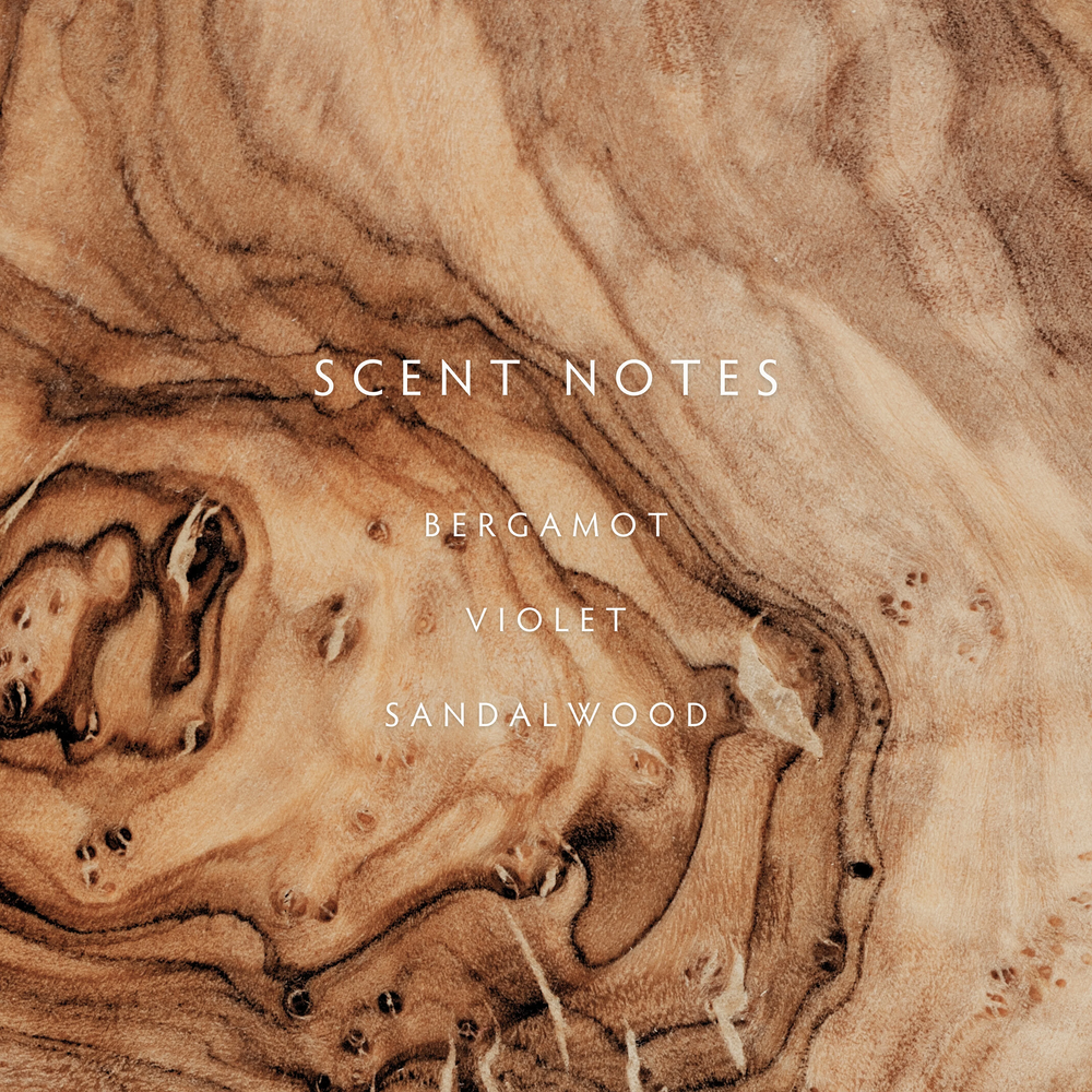 a scent notes description of bergamot violet and sandalwood on a wood background
