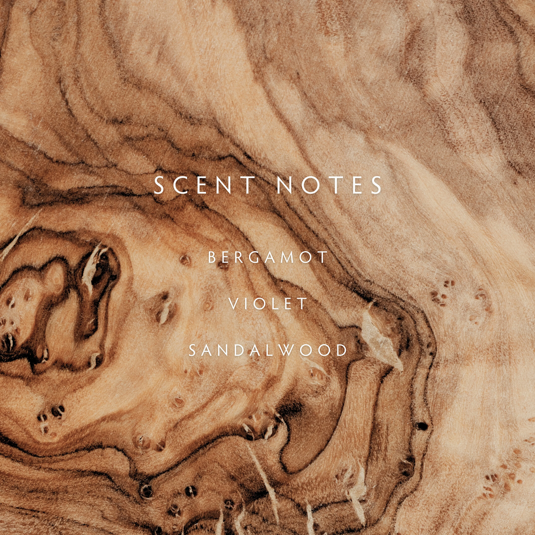 a scent notes description of bergamot violet and sandalwood on a wood background

