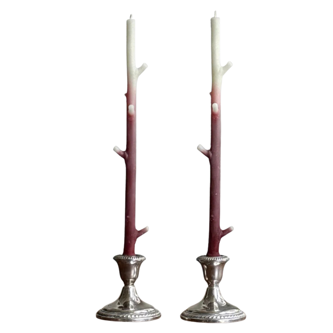 Two branch shaped candles with a white and deep red gradient in silver candle holders