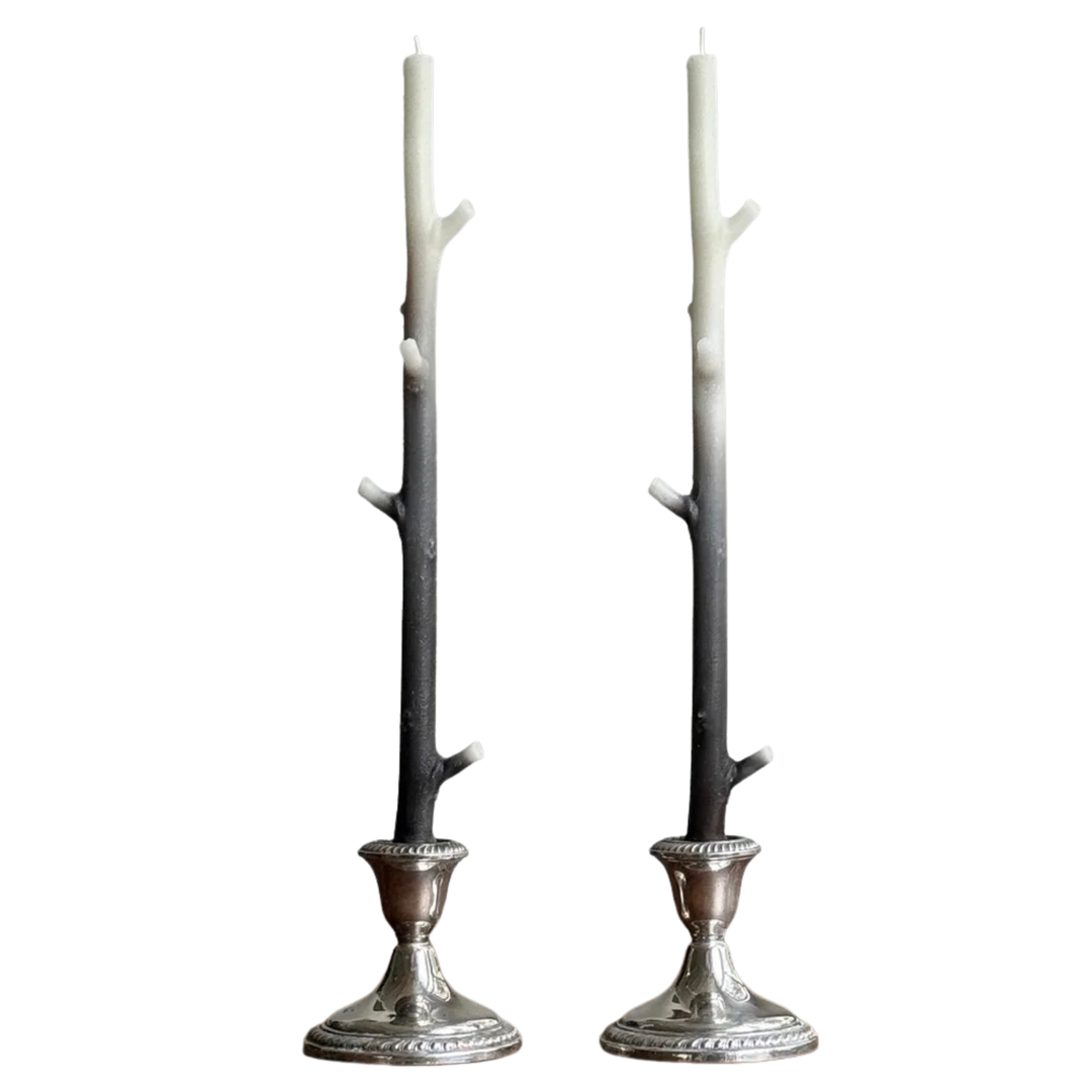 Two branch shaped candles with a white and dark brown gradient in silver candle holders