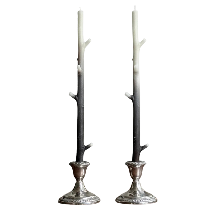 Two branch shaped candles with a white and dark brown gradient in silver candle holders